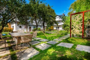 Duży, zielony ogród Domu Wczasowego Rudnik z hamakiem, miejscem do siedzenia i wybrukowaną ścieżką.