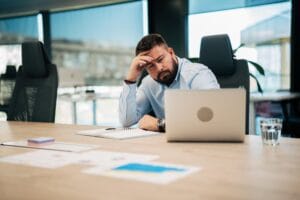 Czy Polacy nienawidzą swojej pracy – zmęczony pracownik przy biurku pokazujący stres i wypalenie zawodowe w pracy